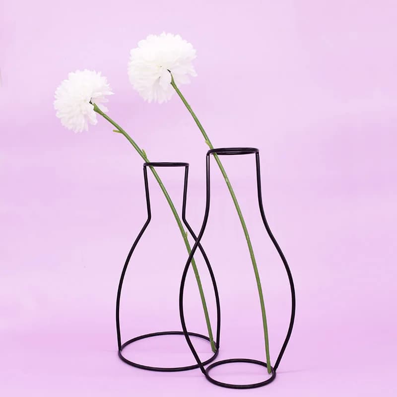 Suportes metálicos pretos para vasos de flores em estilo nórdico com flores rosas