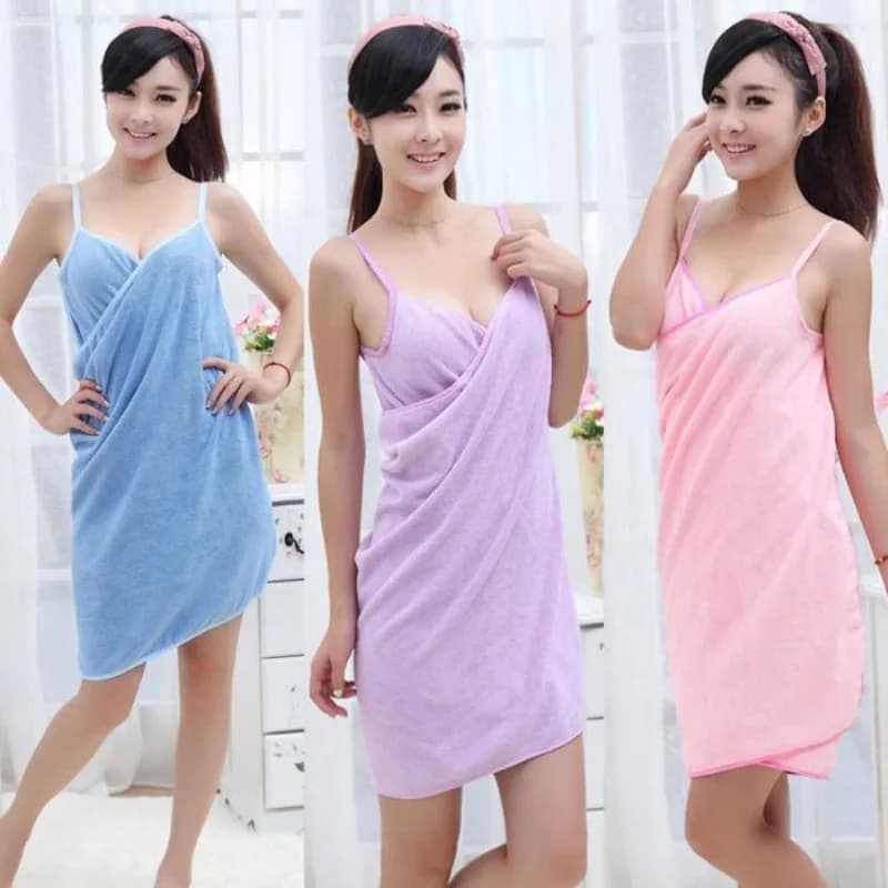 Três mulheres usando toalhas de banho de microfibra azul, roxa e rosa, enroladas como vestidos