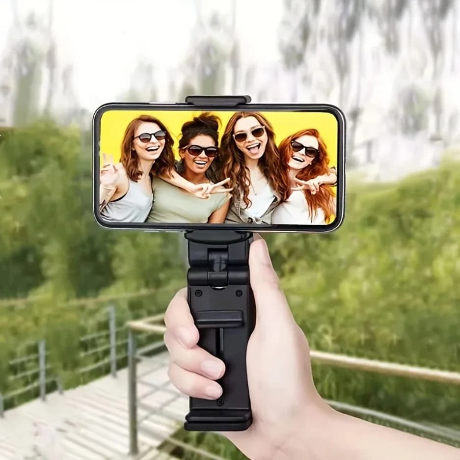 Suporte universal para celular preto sendo segurado na mão com smartphone exibindo foto de grupo