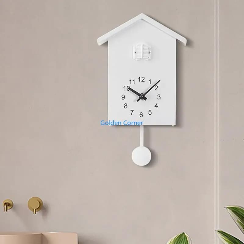 Relógio de parede branco em forma de casa com ponteiro preto, mostrador preto e branco, texto 'Golden Corner' na parte inferior.
