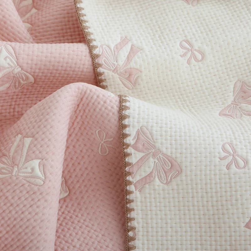 Detalhe da toalha de travesseiro MILANCEL rosa com estampa de laços e acabamento bordado delicado