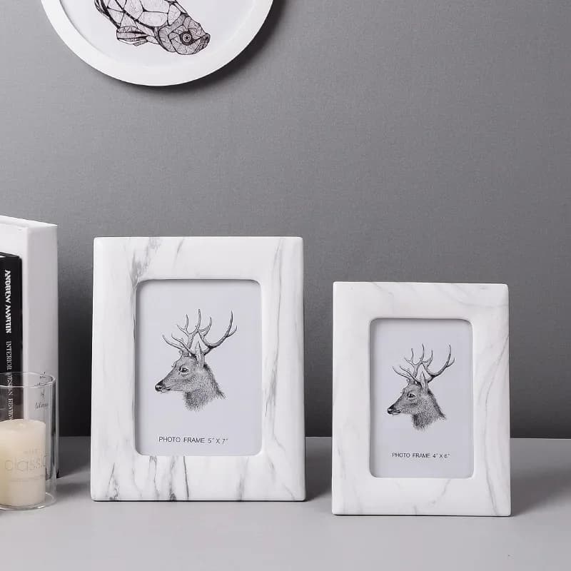 Duas molduras de fotos quadradas brancas com bordas douradas e desenho de cervo
