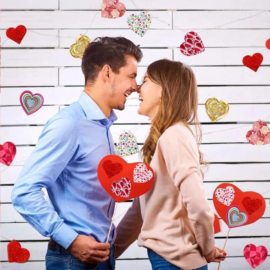 Casal sorrindo com adesivos decorativos de corações coloridos em fundo branco para decoração amorosa