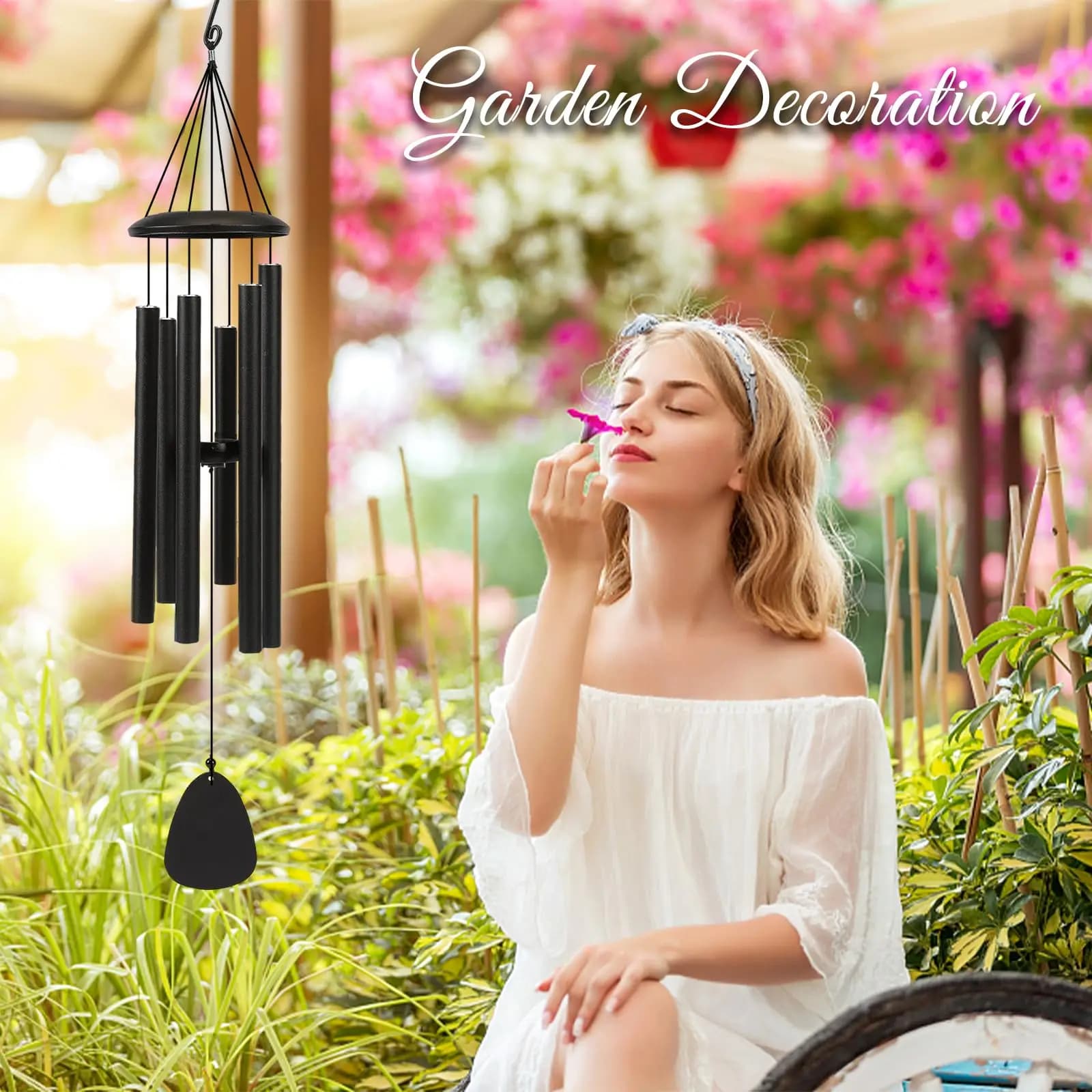 Sino de vento preto decorativo pendurado em jardim com mulher apreciando flor ao fundo