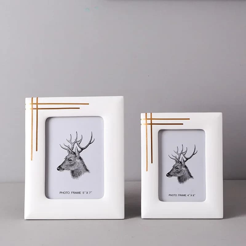 Duas molduras de fotos quadradas brancas com bordas douradas e desenho de cervo