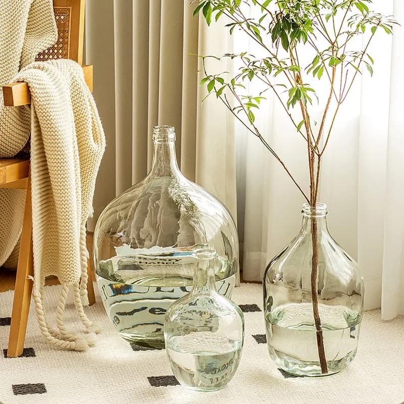 Vasos de vidro transparente para arranjo floral com plantas verdes e água potbelly.