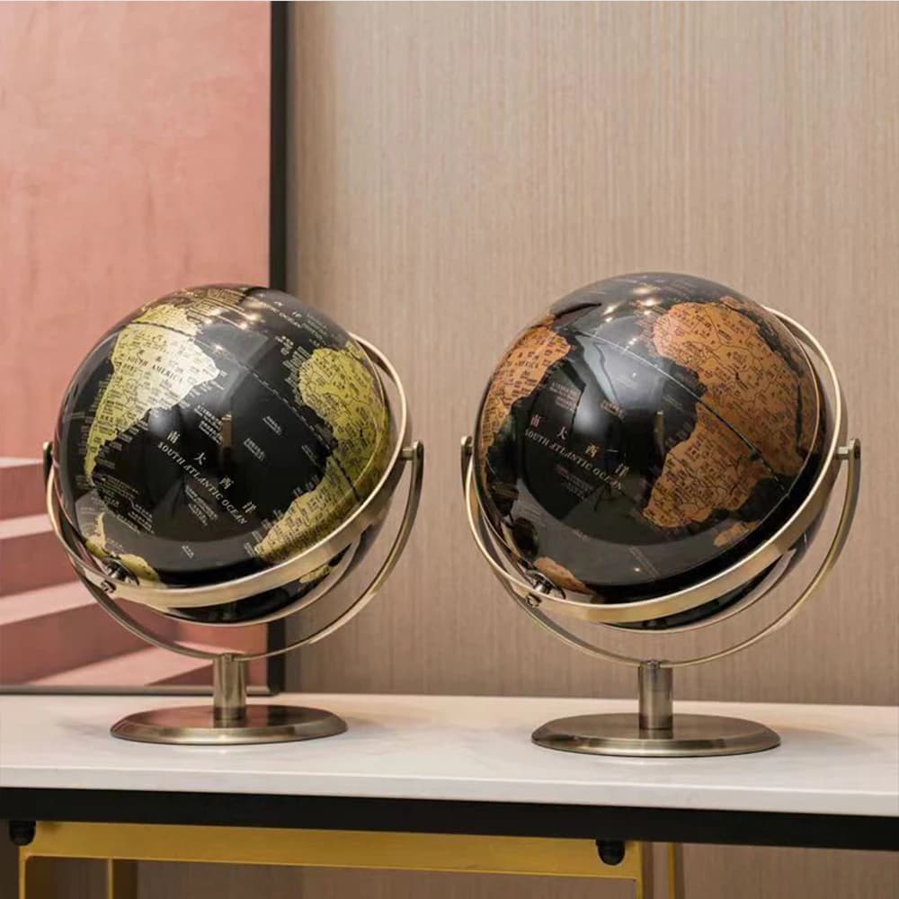 Dois globos terrestres decorativos com cores preto, dourado e verde em base metálica dourada