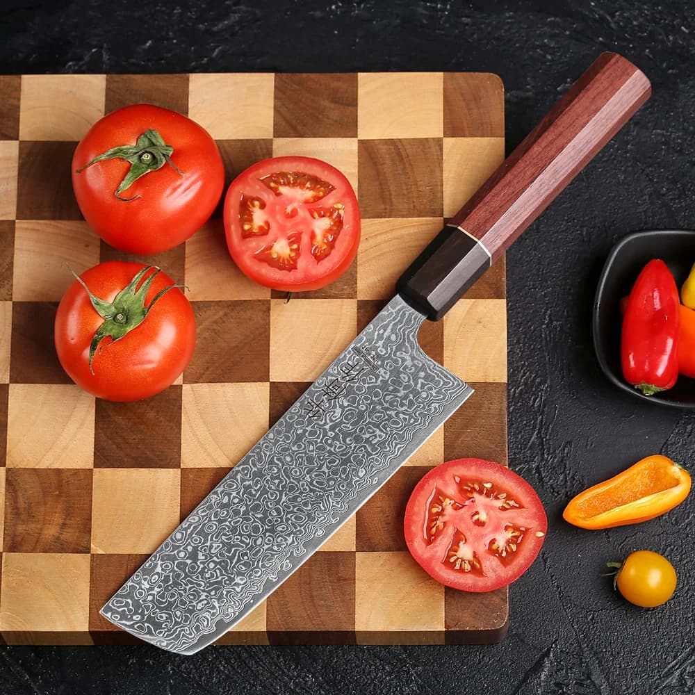 Faca de chef estilo japonês Nakiri de 6,5 polegadas em aço damasco, cabo marrom, embalagem preta com caracteres chineses, abóbora cortada ao lado.