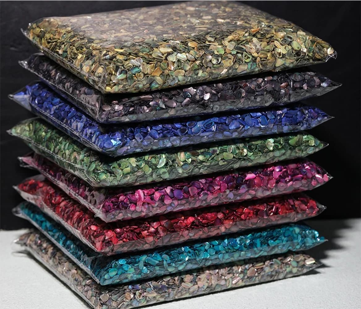 Pacotes empilhados de fragmentos de concha natural para nail art em cores variadas com brilho perolado