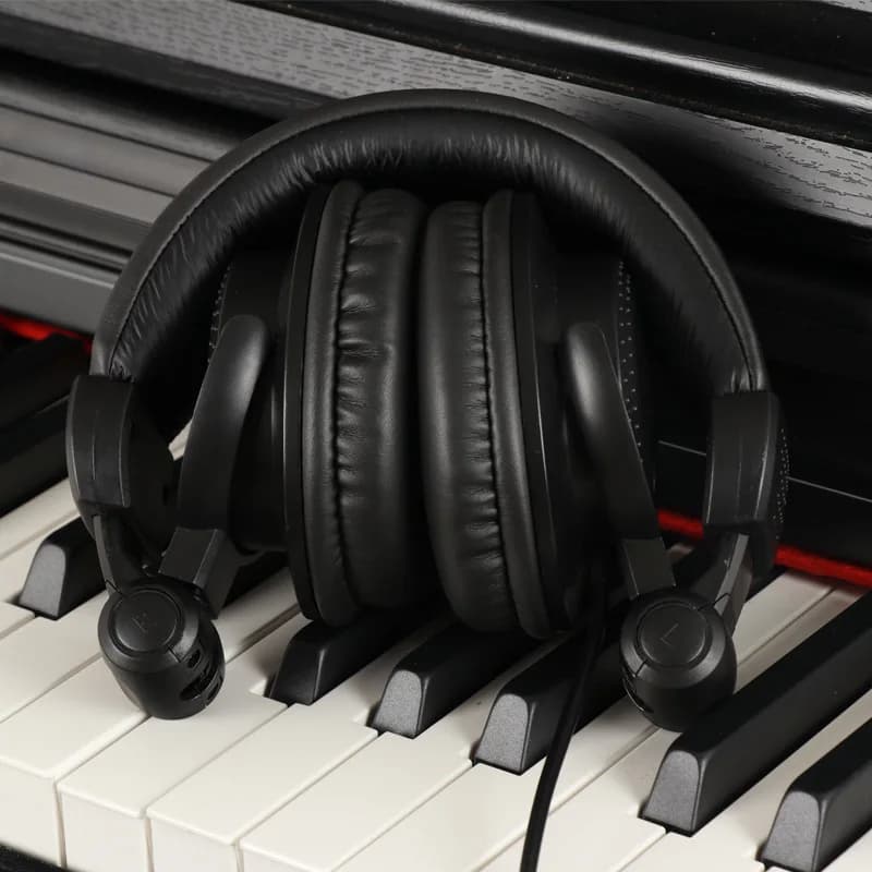 Fone de ouvido preto HP-960B com almofadas acolchoadas e cabo, sobre teclas de piano branco e preto