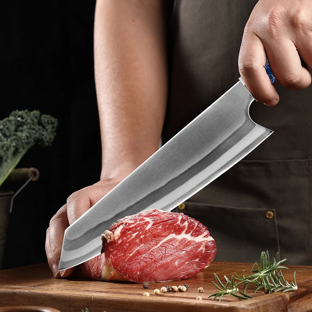 Faca Kiritsuke forjada à mão cortando carne vermelha com cabo azul de resina e detalhes em verde