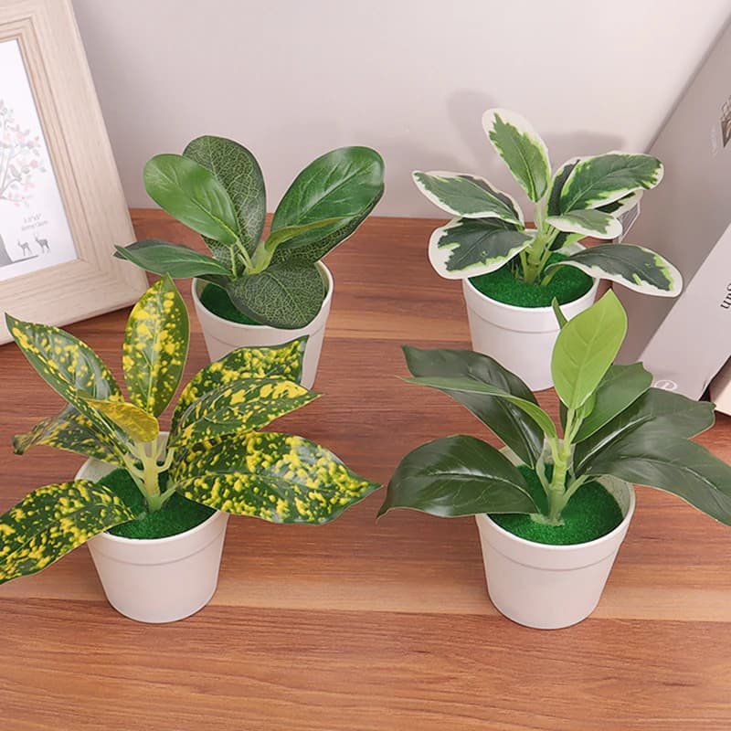 Quatro plantas artificiais em vasos brancos em uma prateleira branca