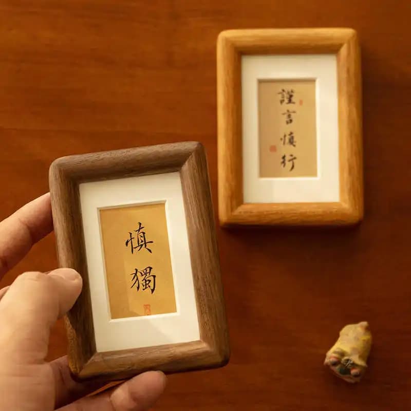 Quadro decorativo minimalista com borda marrom e papel amarelo com caracteres chineses