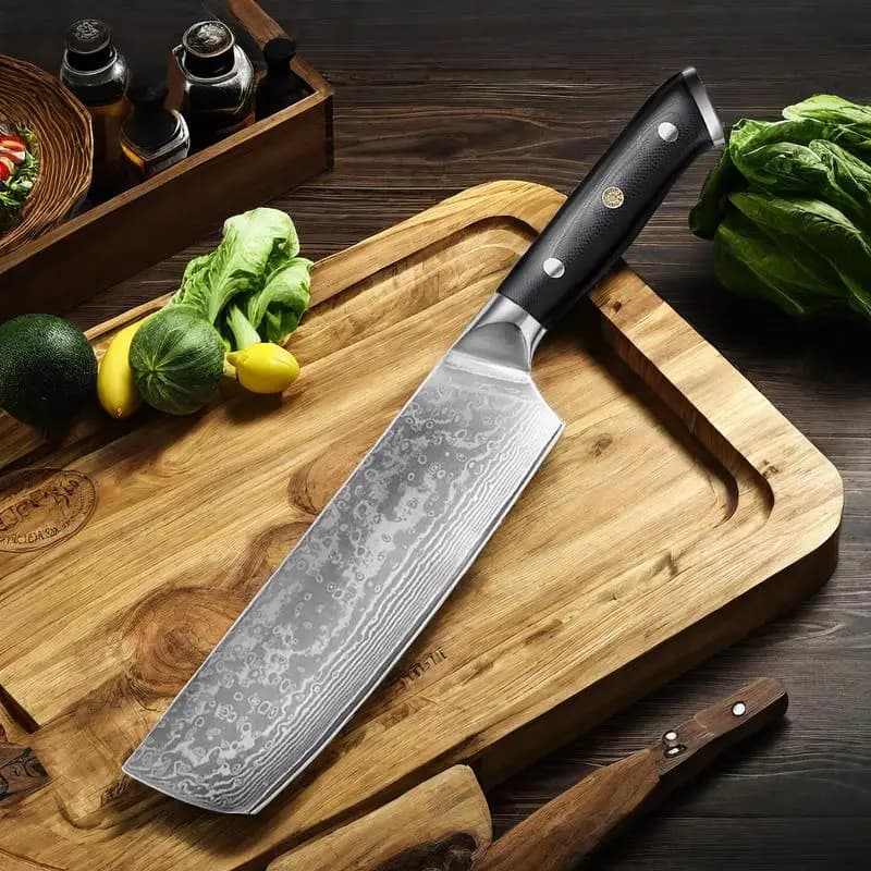 Faca de chef japonesa de 7 polegadas com lâmina damasco e cabo preto sobre tábua de corte com vegetais