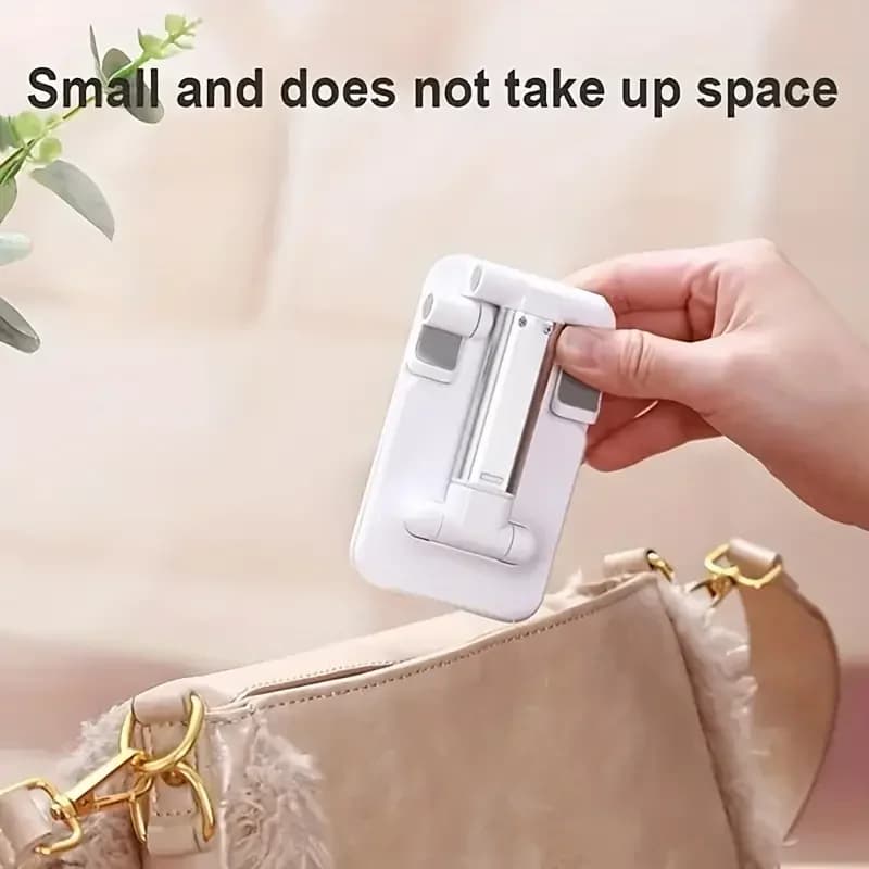 Suporte para celular dobrável compacto em metal preto sendo guardado em bolsa bege