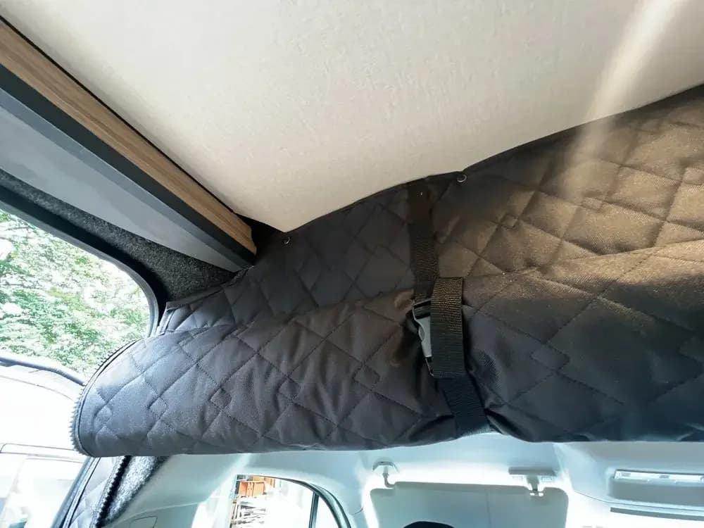 Cortina divisória térmica blackout azul escuro instalada no interior do veículo Fiat Ducato com fixação por cinto ajustável