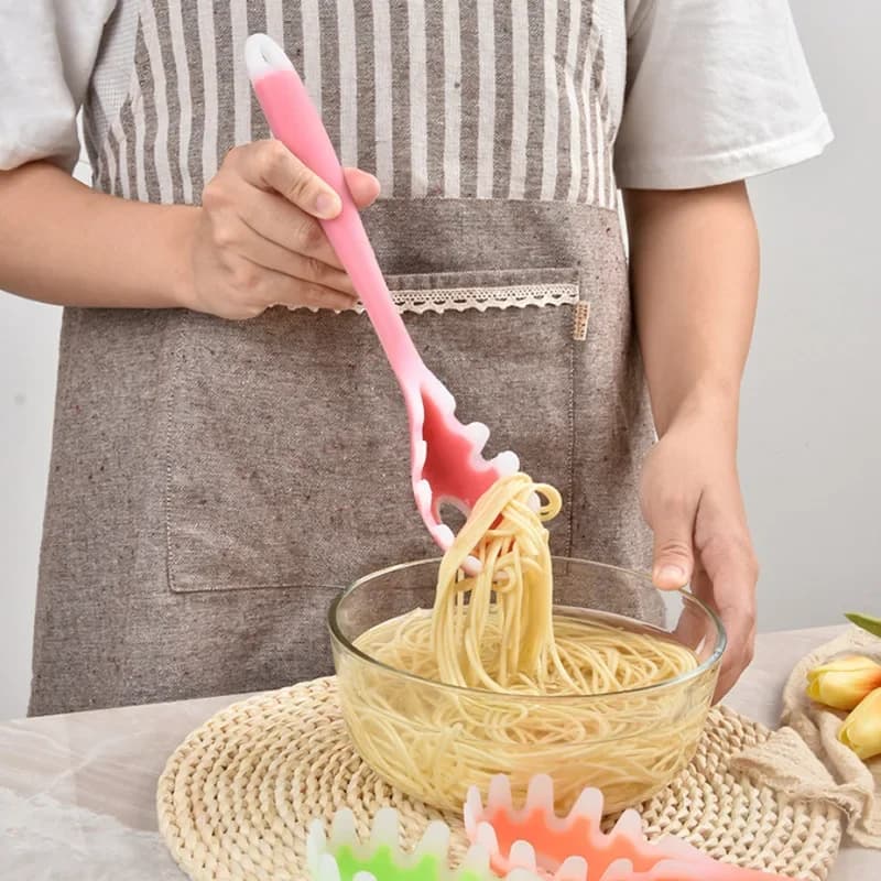 Coador de macarrão rosa em silicone sendo usado para servir macarrão em tigela de vidro