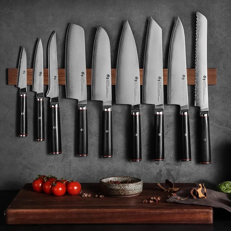 Conjunto de facas de cozinha com cabo preto e lâminas de aço inoxidável, exibidas em um suporte de madeira