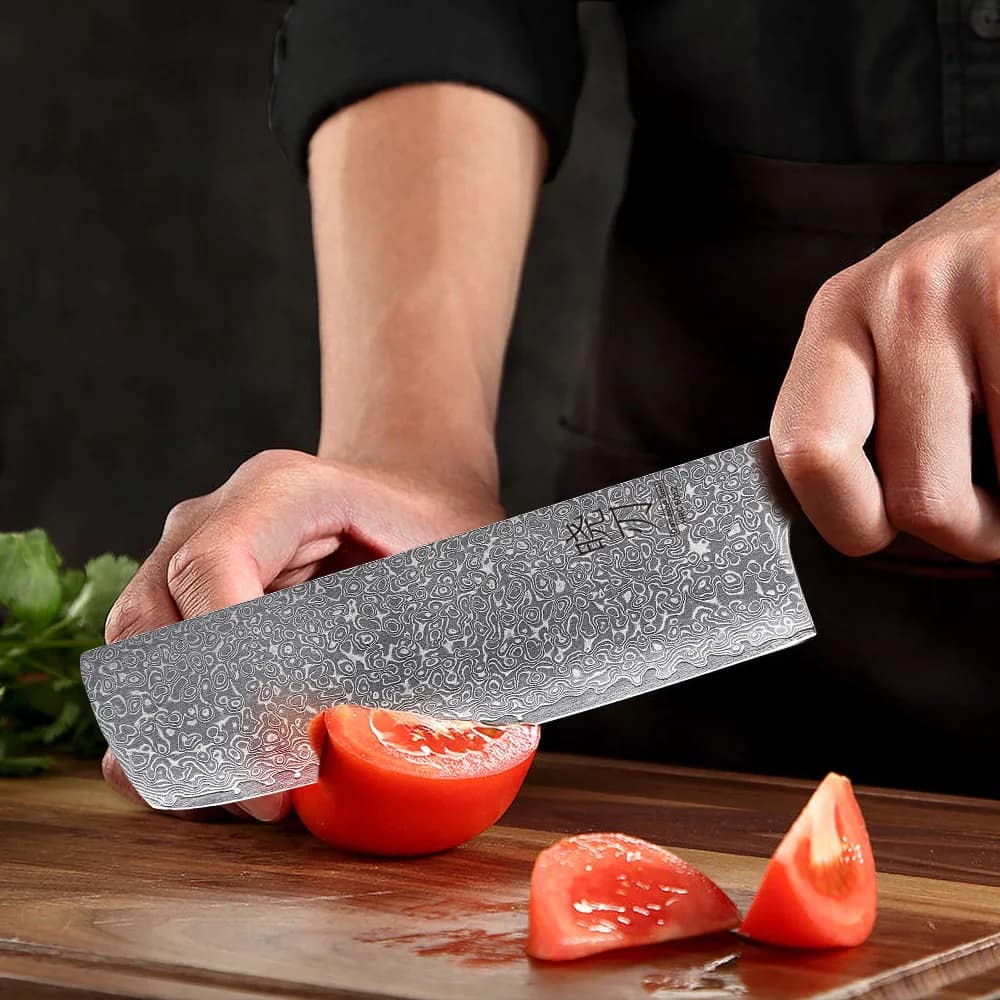 Faca japonesa Nakiri azul em aço damasco 67 camadas cortando tomate na tábua de madeira