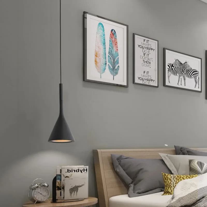 Luminária pendente preta fosca com luz LED direcionada para baixo em quarto decorado com quadros na parede