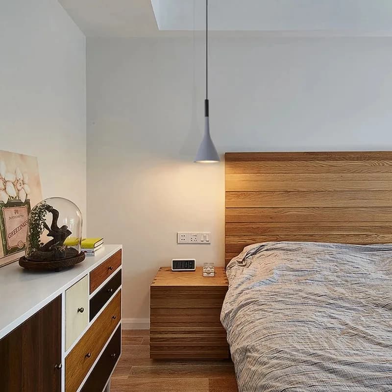 Luminária pendente cinza com luz LED direcionada para baixo em quarto com decoração minimalista