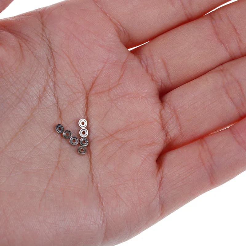 Rolamentos de esferas miniatura 681ZZ em metal prateado sobre palma da mão para comparação de tamanho
