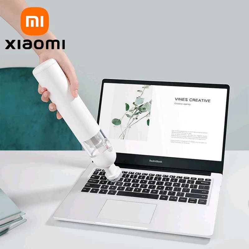 Aspirador de pó portátil Xiaomi em uso, limpando um laptop