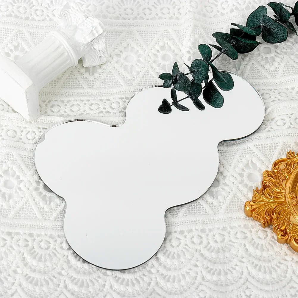 Espelho decorativo Jácotei irregular acrílico transparente com folhas verdes e moldura dourada sobre tecido branco