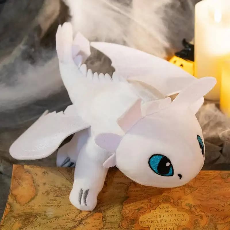 Pelúcia dragão fofo branco com olhos azuis em ambiente decorativo com mapa e velas