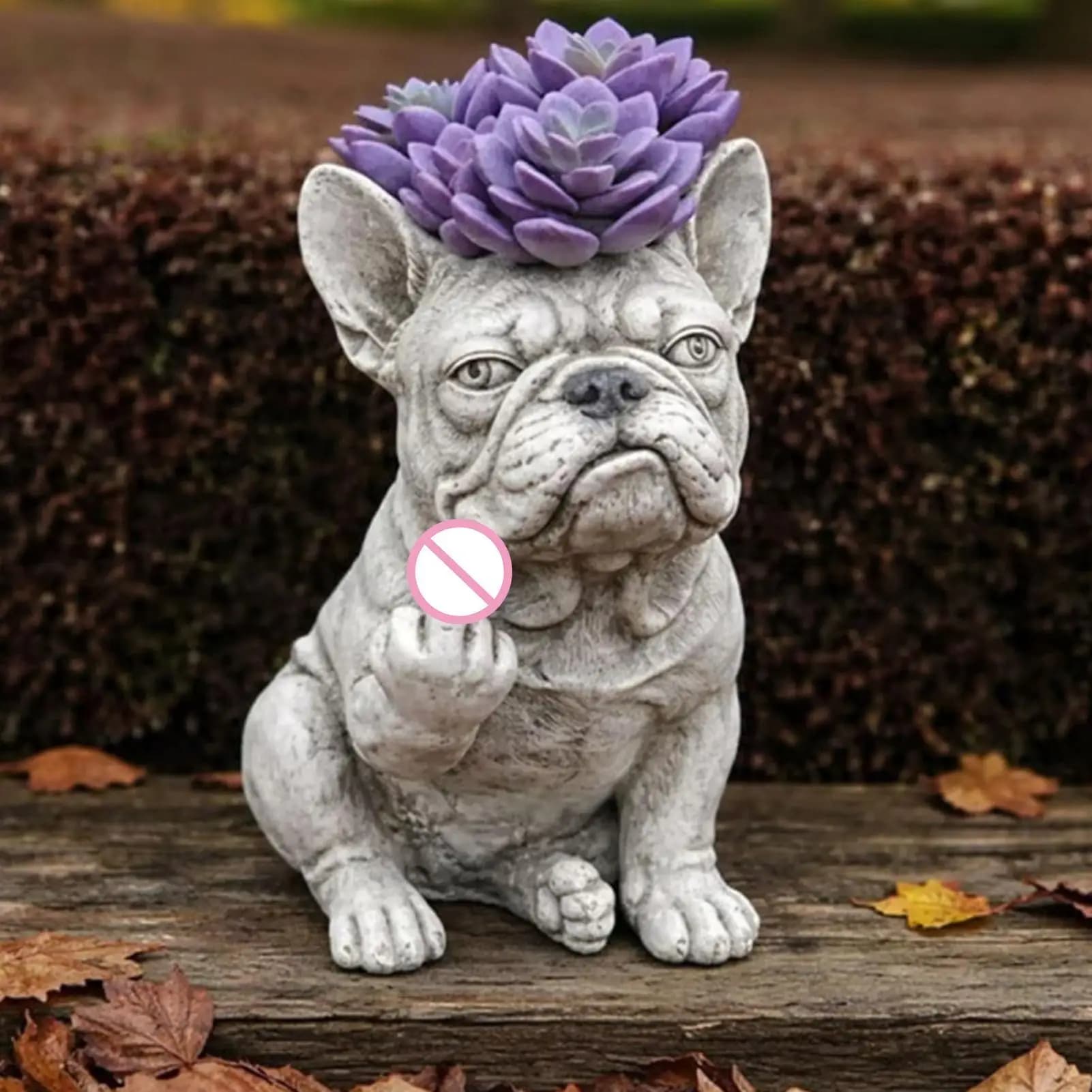Estátua de bulldog francês cinza para plantas com suculenta roxa e folhas caídas ao fundo