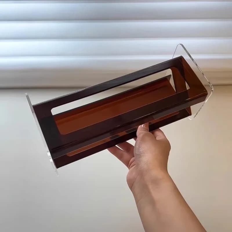 Suporte de controle remoto em acrílico transparente com base marrom visto de cima, sem controles
