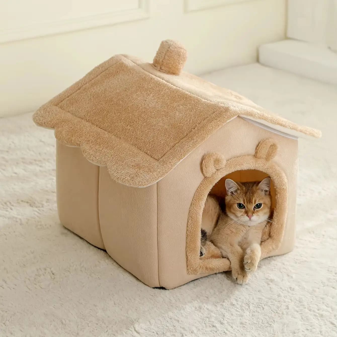 Cama dobrável e lavável para gatos em formato de casa, cor bege, com gato amarelo dentro