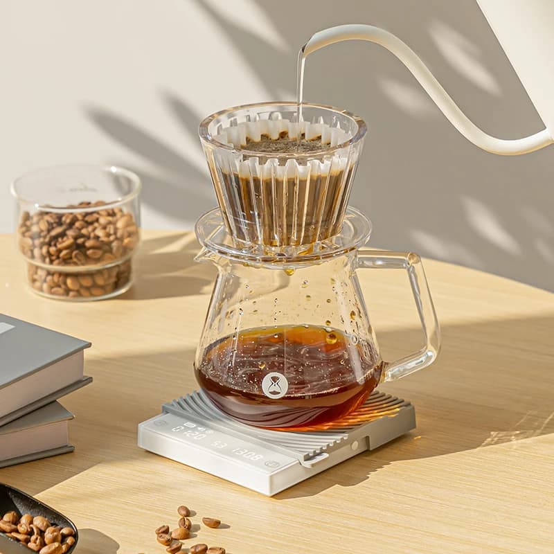 Balança Timemore Espelho Mini branca com display LCD pesando café coado em jarra de vidro transparente