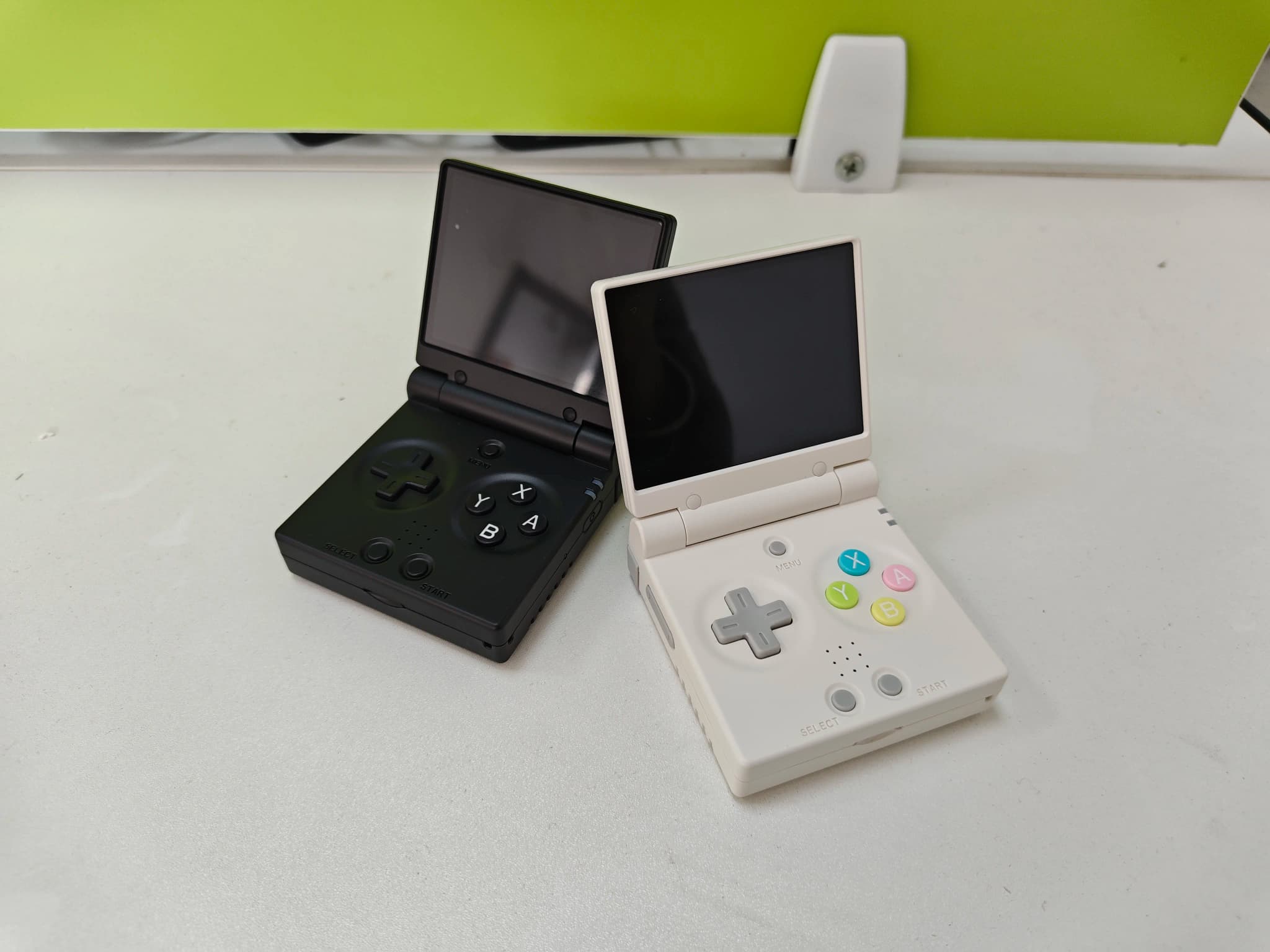 Consoles portáteis Miyoo Mini Flip dobráveis em preto e branco com botões coloridos e tela 2.8 polegadas