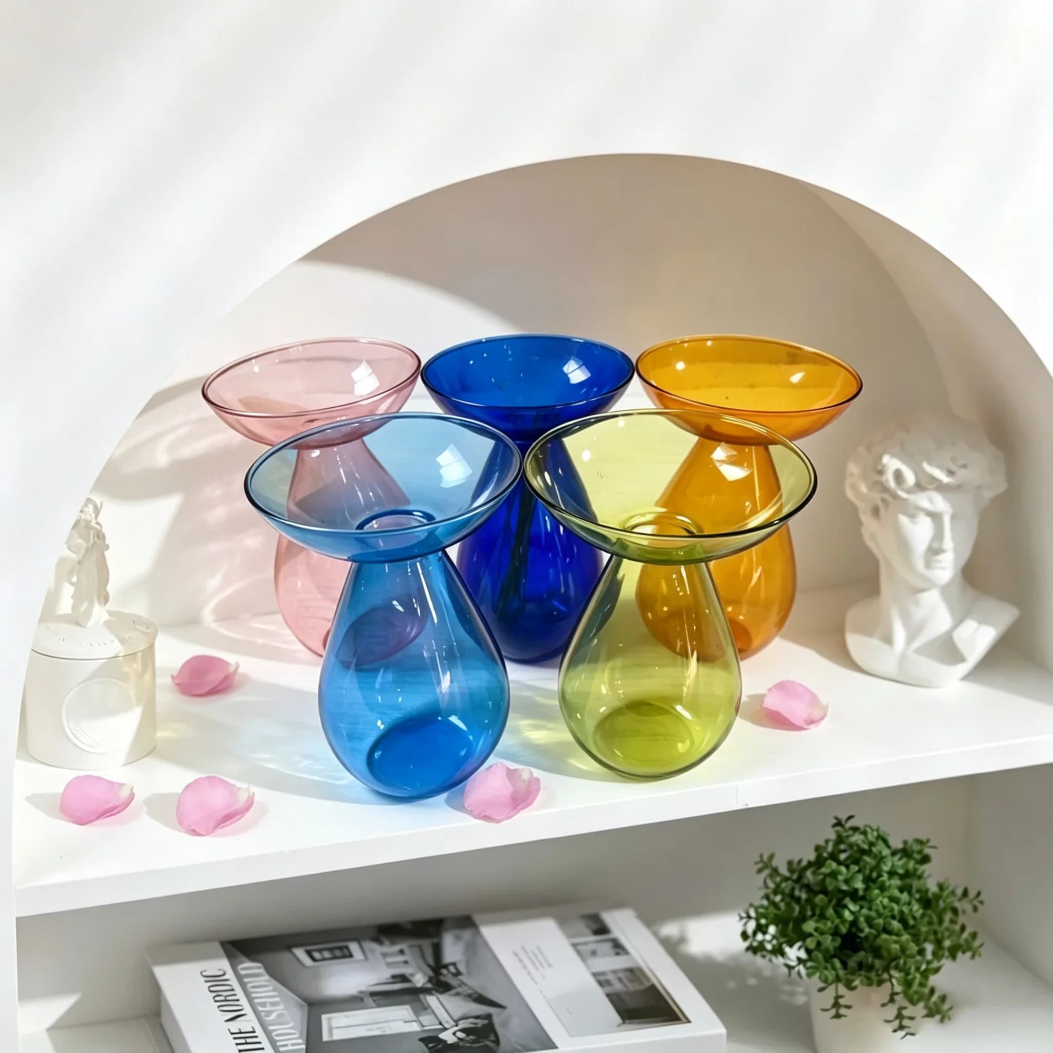 Vasos de vidro colorido em forma de abacate em uma prateleira branca