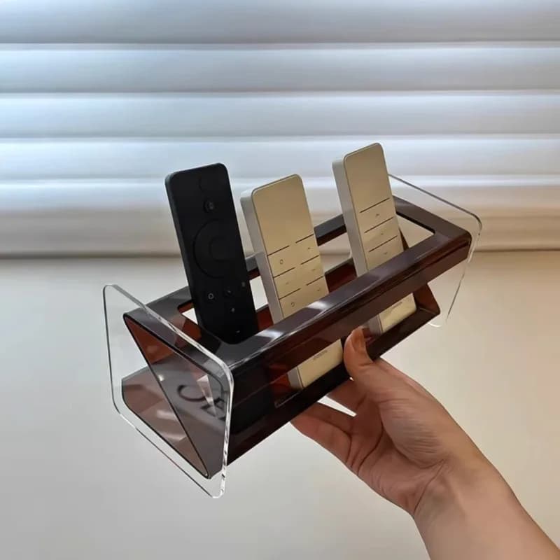 Suporte de controle remoto multifuncional em acrílico transparente com base marrom e três controles remotos