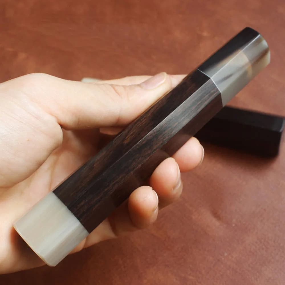 Alça para faca japonesa octogonal em ébano branco com chifre de yak preta sendo segurada na mão