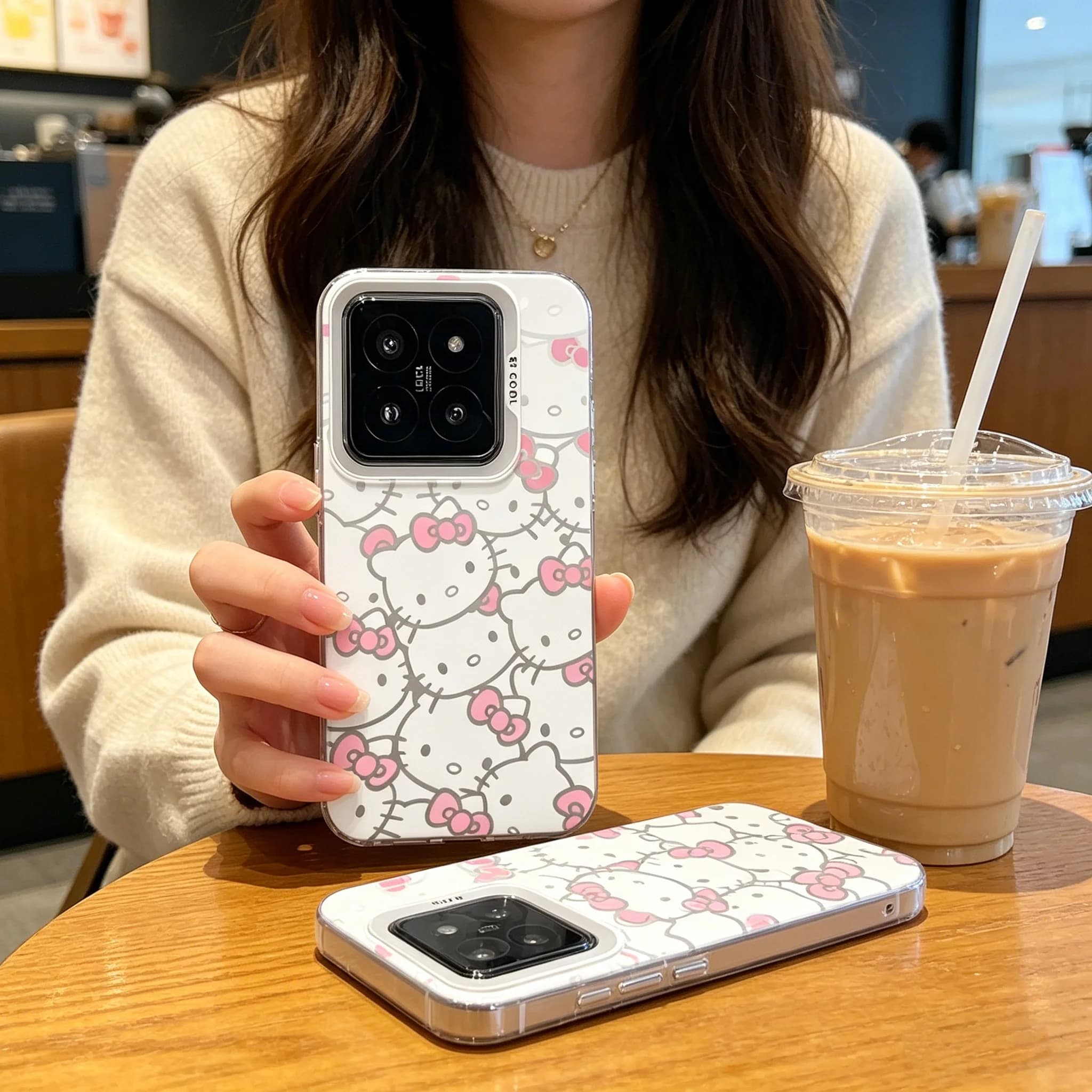 Pessoa segurando Xiaomi Redmi Note 14 Pro com capa Sanrio Sweet Hello Kitty branca e rosa em café