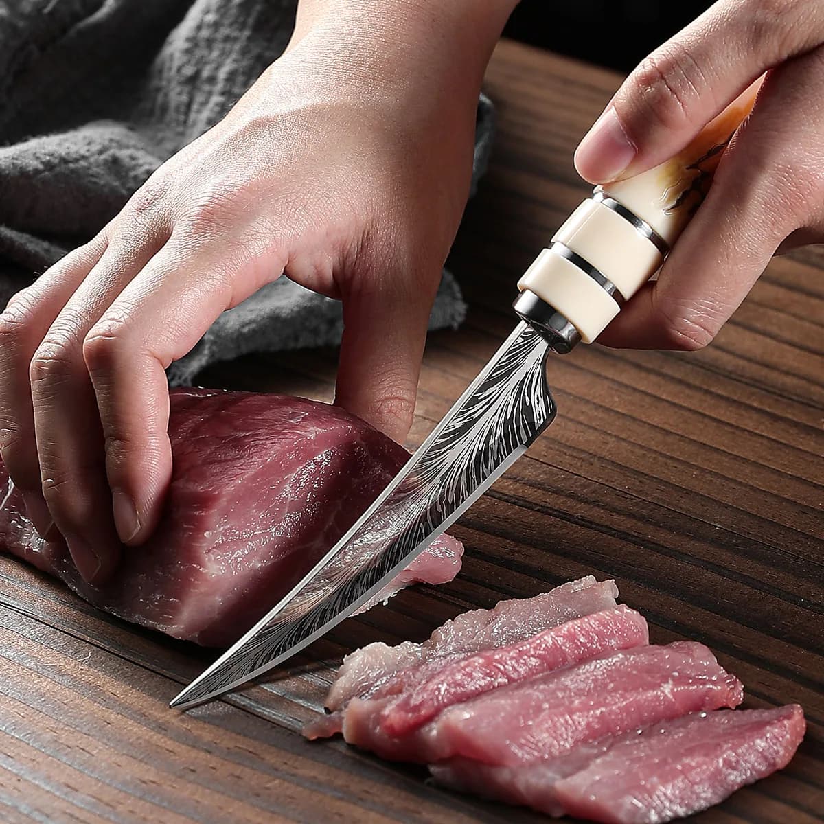 Faca de desossa com lâmina curvada e cabo em madeira textura Damasco fatiando carne vermelha fresca