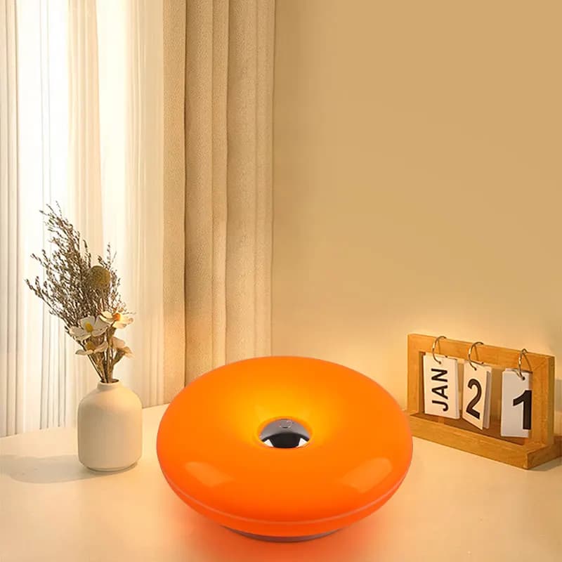 Luminária de mesa em forma de donut laranja, com flores e calendário.