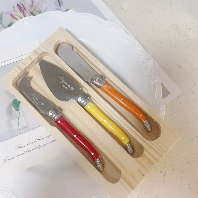 Facas para queijo Laguiole com cabos coloridos em vermelho, amarelo e laranja em embalagem de madeira