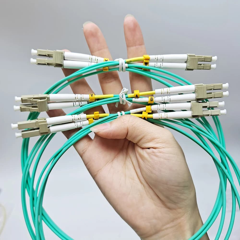Mão segurando cabo fibra óptica OM3 LC UPC duplex multimodo ciano com conectores LC brancos kit 10 peças