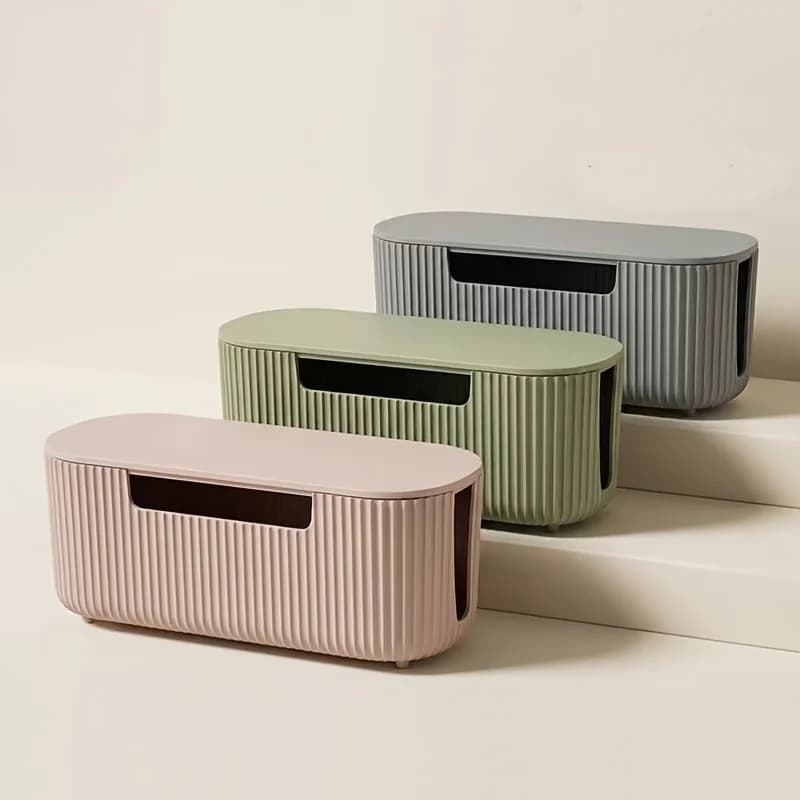 Caixas organizadoras de cabos em ABS, cores rosa, verde e cinza, em plano inclinado.