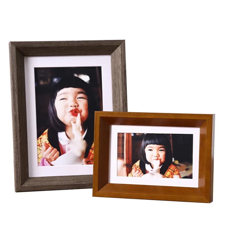 Conjunto com 2 porta-retratos minimalistas em madeira cinza e marrom exibindo fotos de criança sorrindo