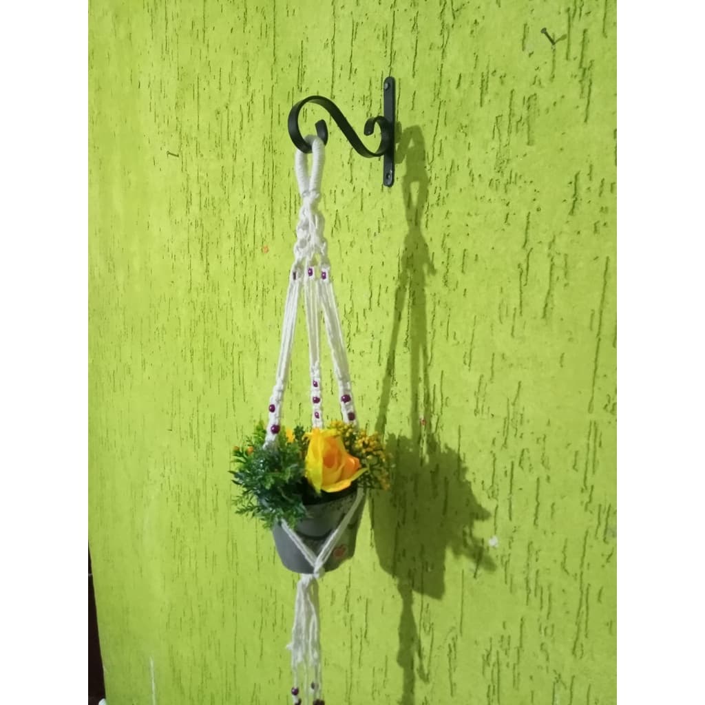 Suporte para vaso de plantas em macramê com flores amarelas e verdes