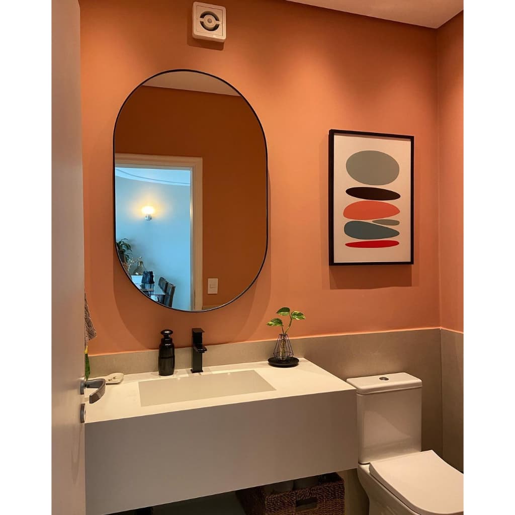Espelho oval decorativo com borda preta em banheiro laranja