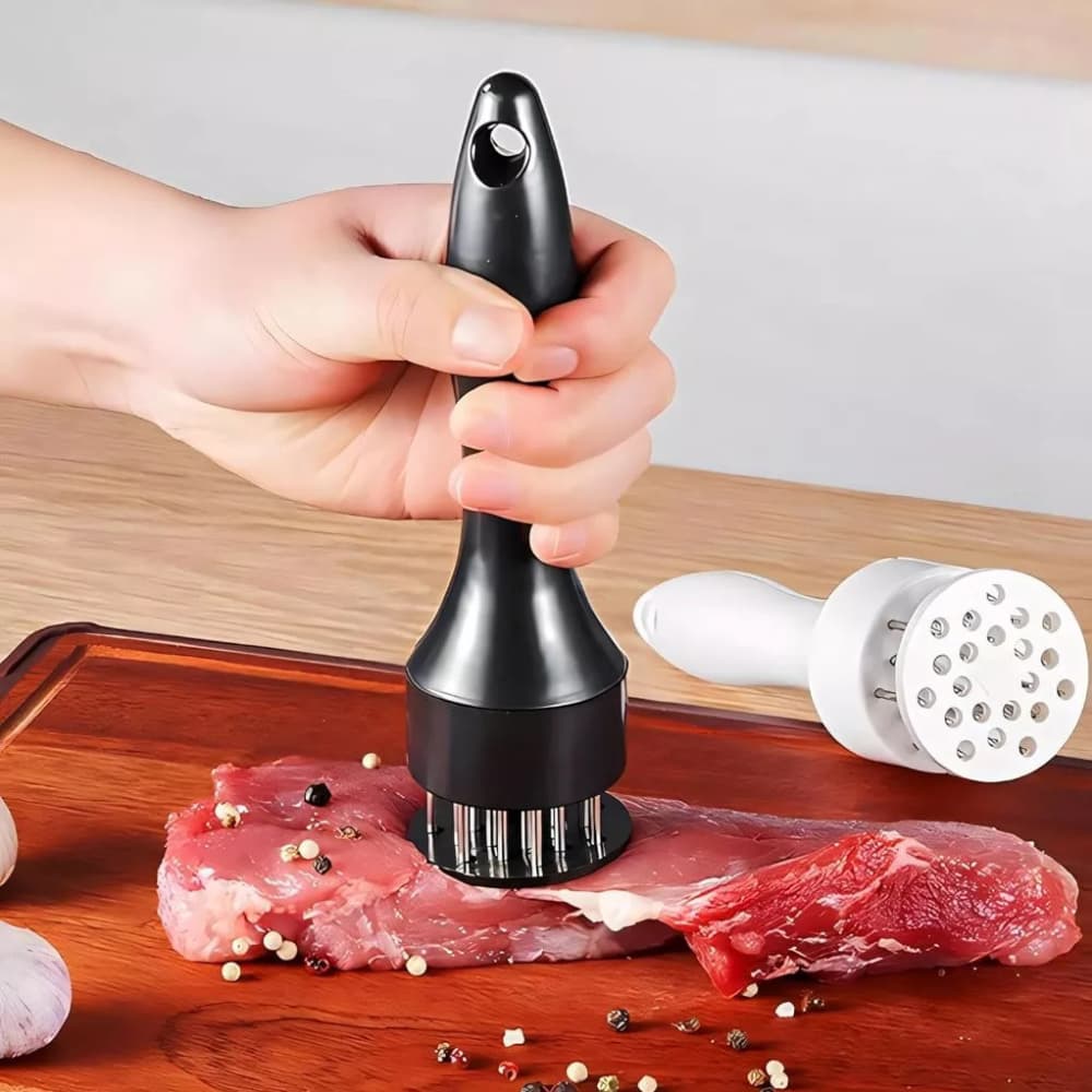 Amaciador de carne bife manual com furador de aço inox preto sobre carne em tabuleiro de madeira