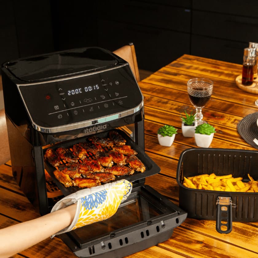 Fritadeira Digital Itatiaia 4 em 1 com frango assado e batatas fritas em uma mesa de madeira