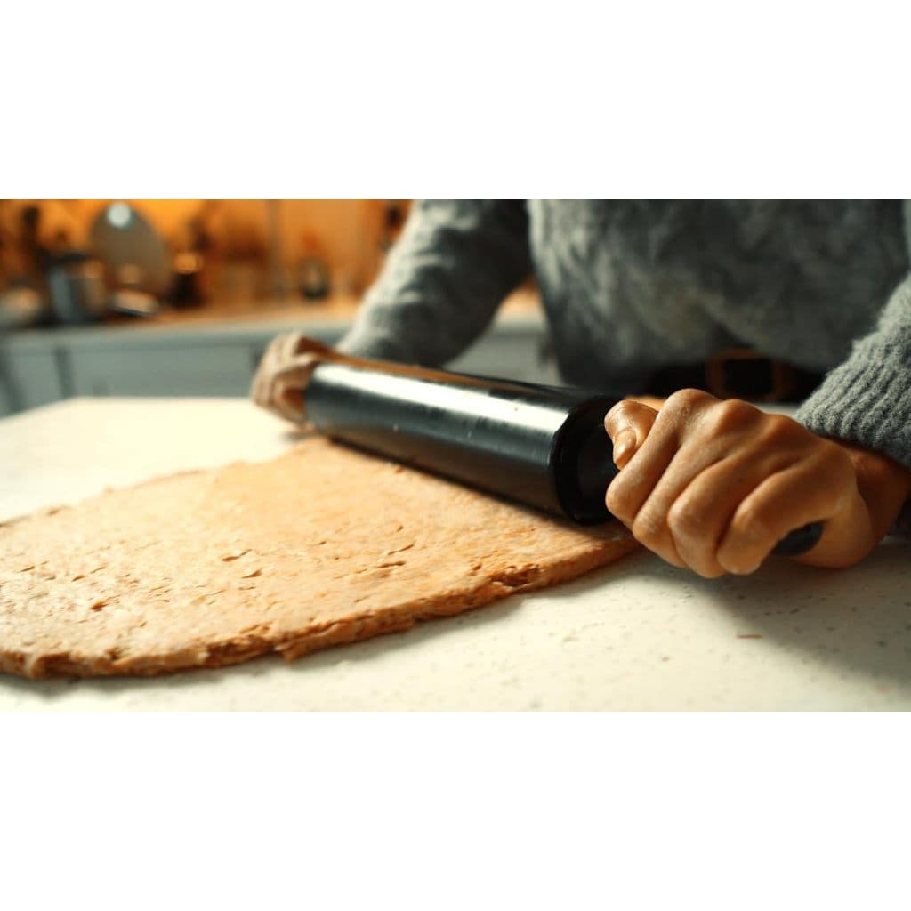 Rolo abridor de massa de 40 cm em silicone antiaderente preto sendo usado para abrir massa de pizza