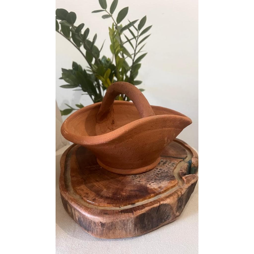 Vaso de barro estilo cesta marrom em pé sobre um pedaço de madeira